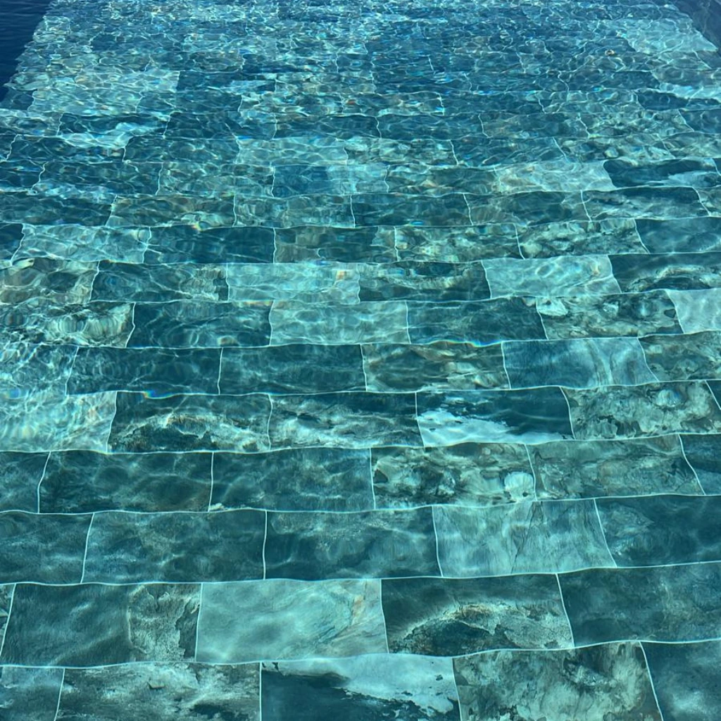 Revêtement de piscine en pierre de Bali immergée, effet d'eau limpide et nuances naturelles changeantes selon la lumière