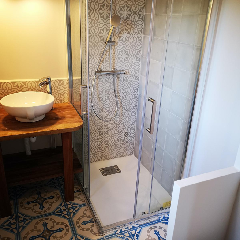 Salle de bain avec douche à l’italienne et carreaux de ciment à motifs muraux et au sol.