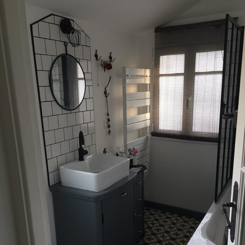 Salle de bain élégante avec carreaux de ciment au sol et murs en zelliges blancs.