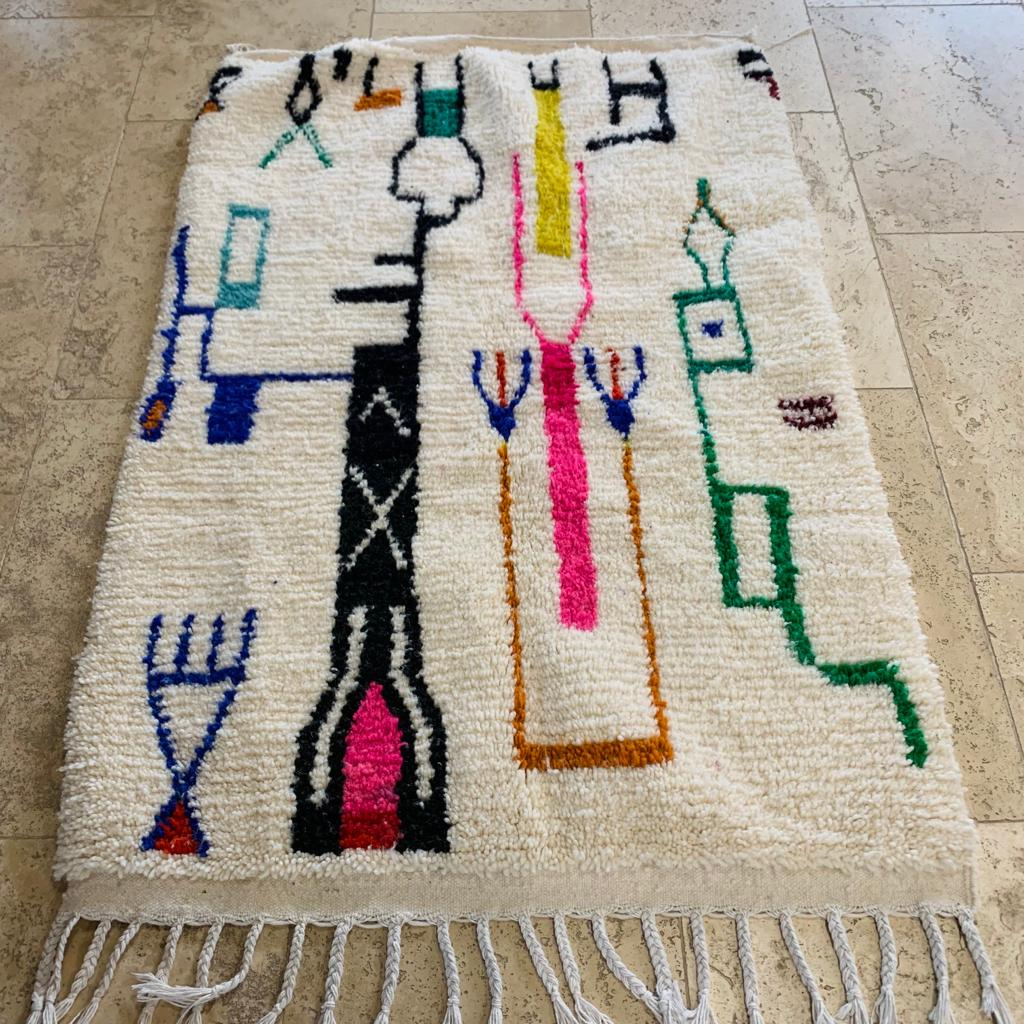 Tapis Beni Ouarain blanc à motifs géométriques colorés tissés à la main sur sol en pierre naturelle