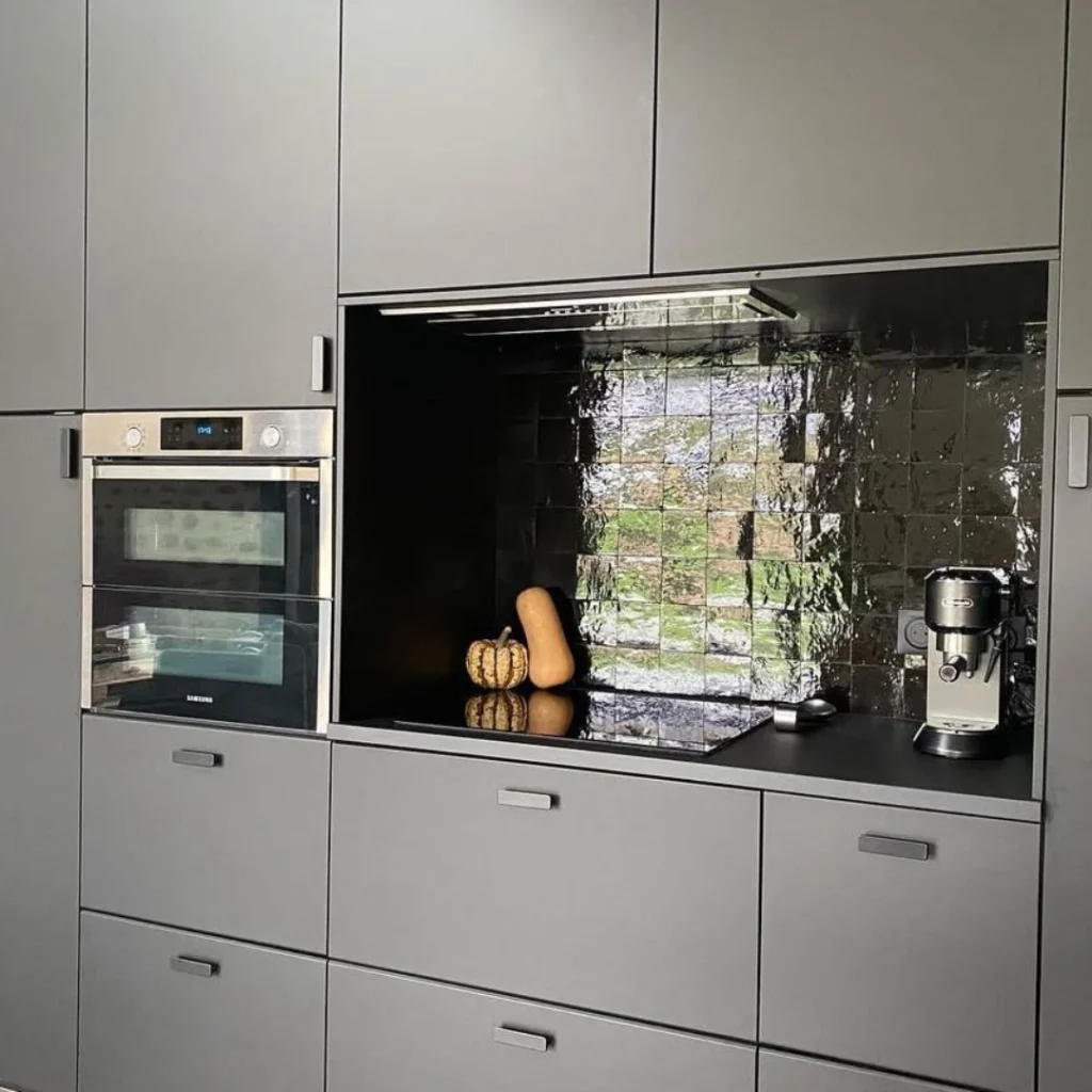 Zellige noir marocain brillant, crédence de cuisine grise moderne avec électroménager intégré.