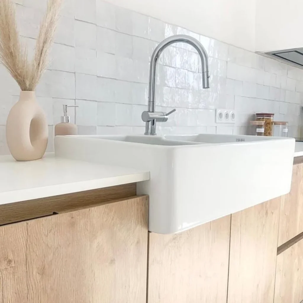 Cuisine moderne avec crédence en zellige blanc nuancé et plan de travail en bois clair.