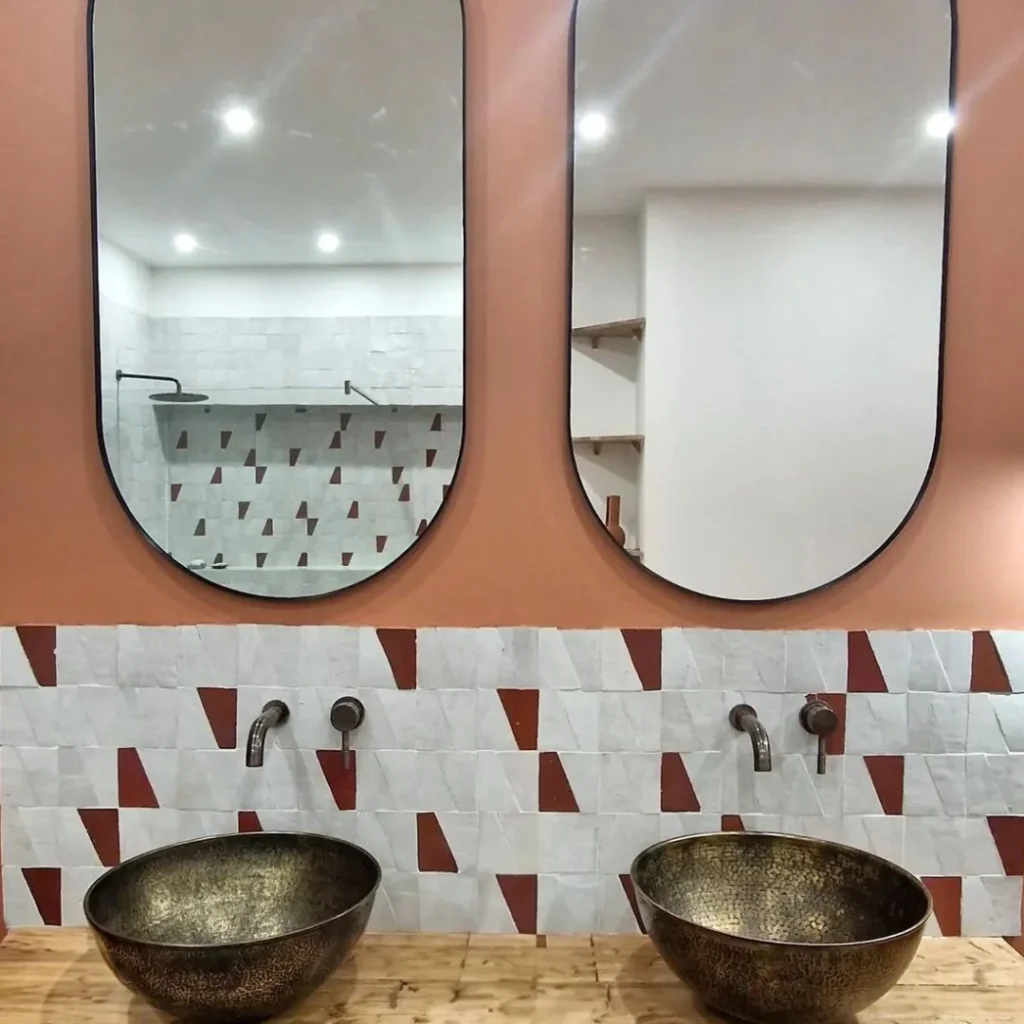 Salle de bain rétro avec zellige blanc et rouge brique, doubles vasques en laiton martelé.