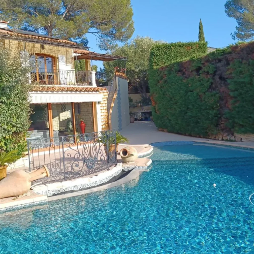 Maison méditerranéenne avec piscine et terrasse en pierre naturelle, carrelage et éléments artisanaux.