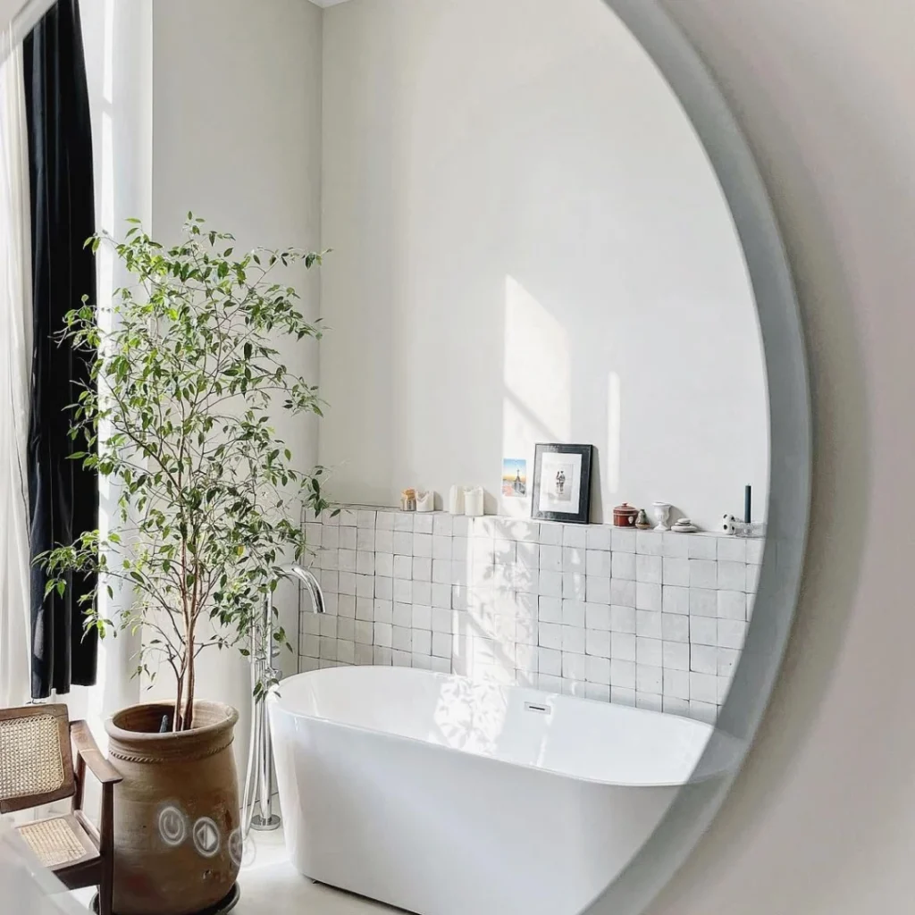 Salle de bain moderne avec zellige blanc cassé, robinetterie noire et miroir rond.