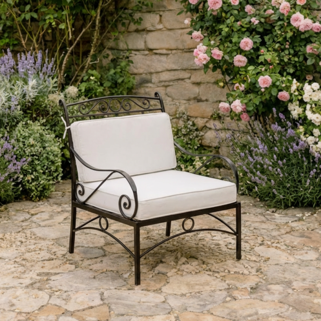 Fauteuil en fer forgé noir avec coussins beiges, style romantique, installé dans un jardin fleuri en pierre naturelle.