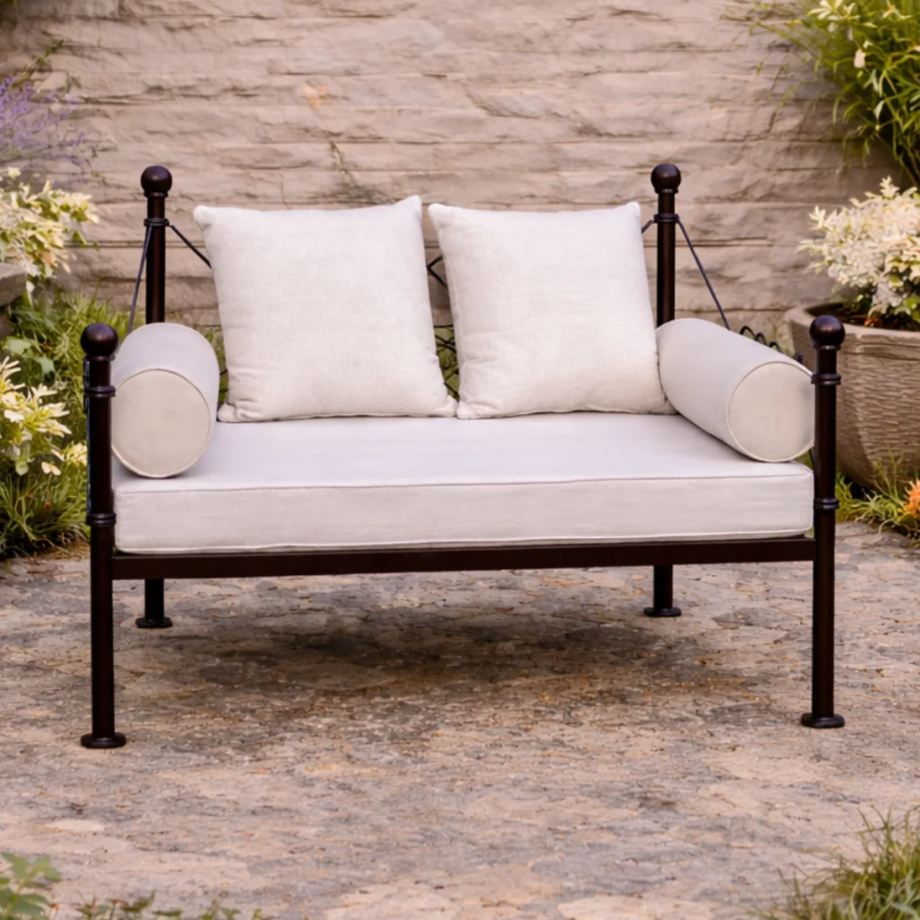 Banquette extérieure en métal noir avec coussins clairs installée sur patio en pierre naturelle.