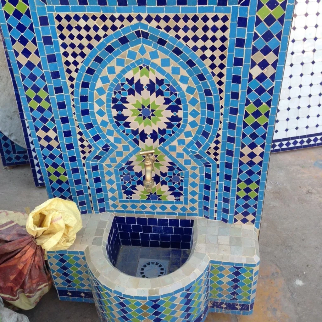 fontaine en zellige bleu en cours d’installation avec crachoir en laiton et mosaïque artisanale