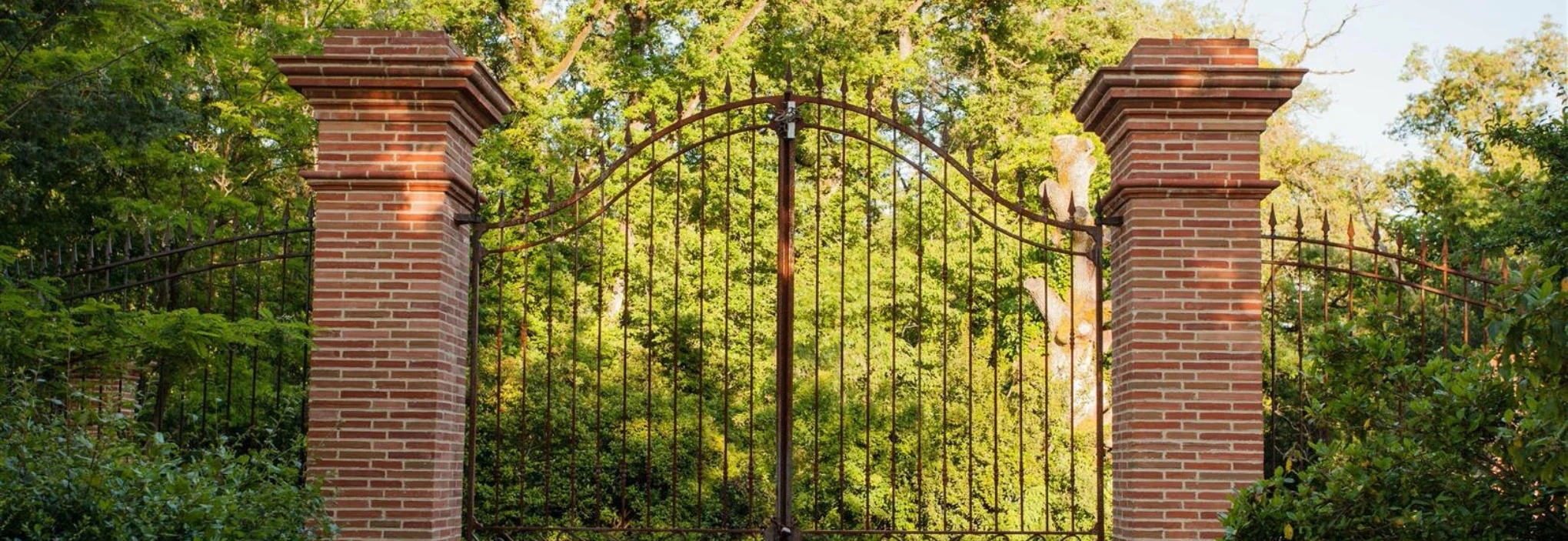 portail en fer forgé avec piliers en brique rouge et têtes de piliers moulurées