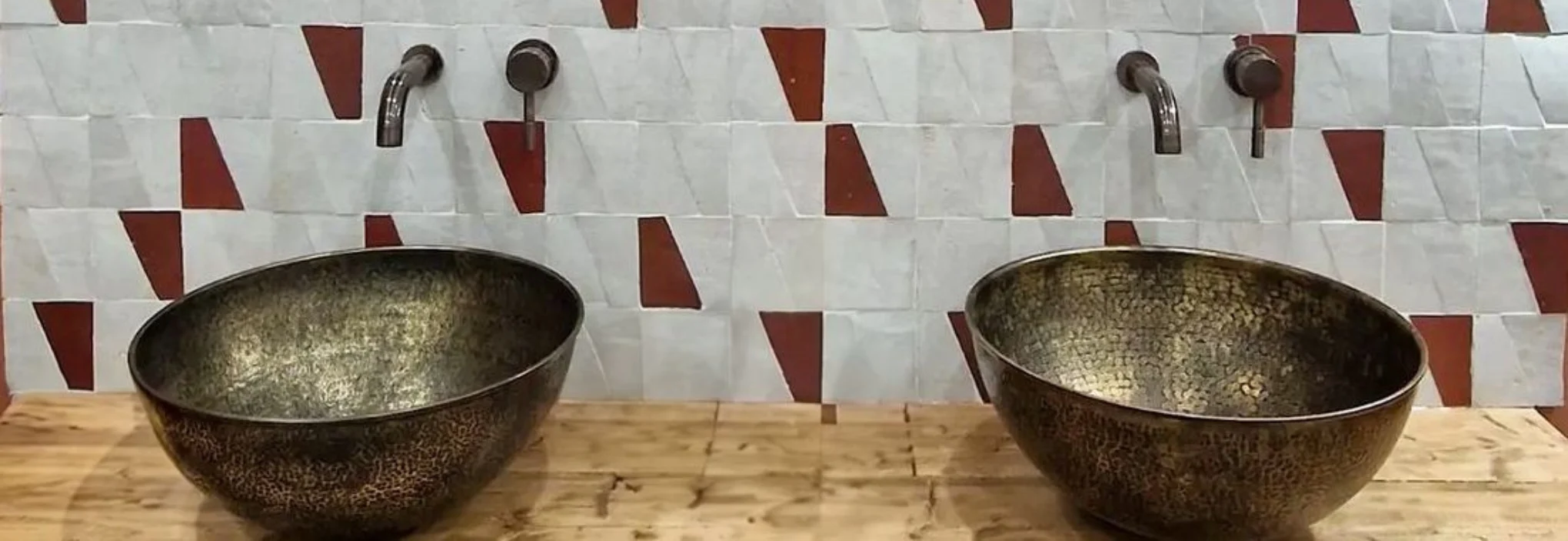 Zellige-marocain-–-Mur-de-salle-de-bain-artisanal-avec-vasques-en-laiton Mur en zellige marocain blanc et rouge de Fès, carrelage artisanal en terre cuite émaillée derrière deux vasques en laiton