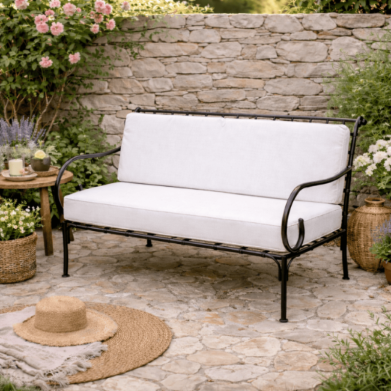 Banquette en fer forgé avec coussins blancs dans un jardin