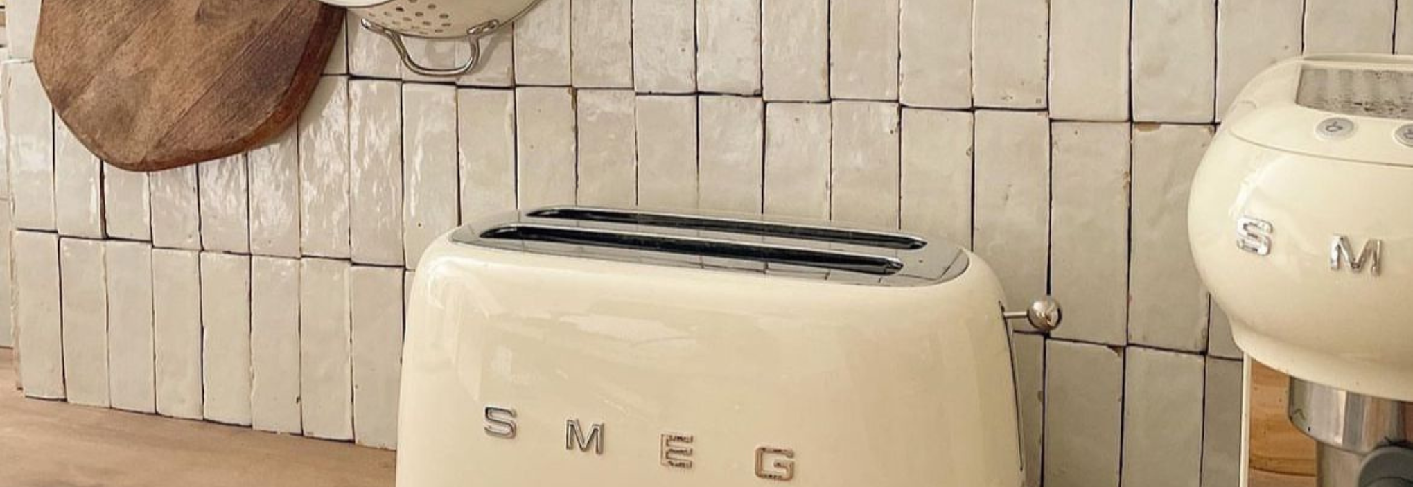 Crédence de cuisine en bejmat blanc artisanal de Fès, carrelage marocain en terre cuite émaillée, avec grille-pain et machine à café Smeg beige sur plan de travail en bois.