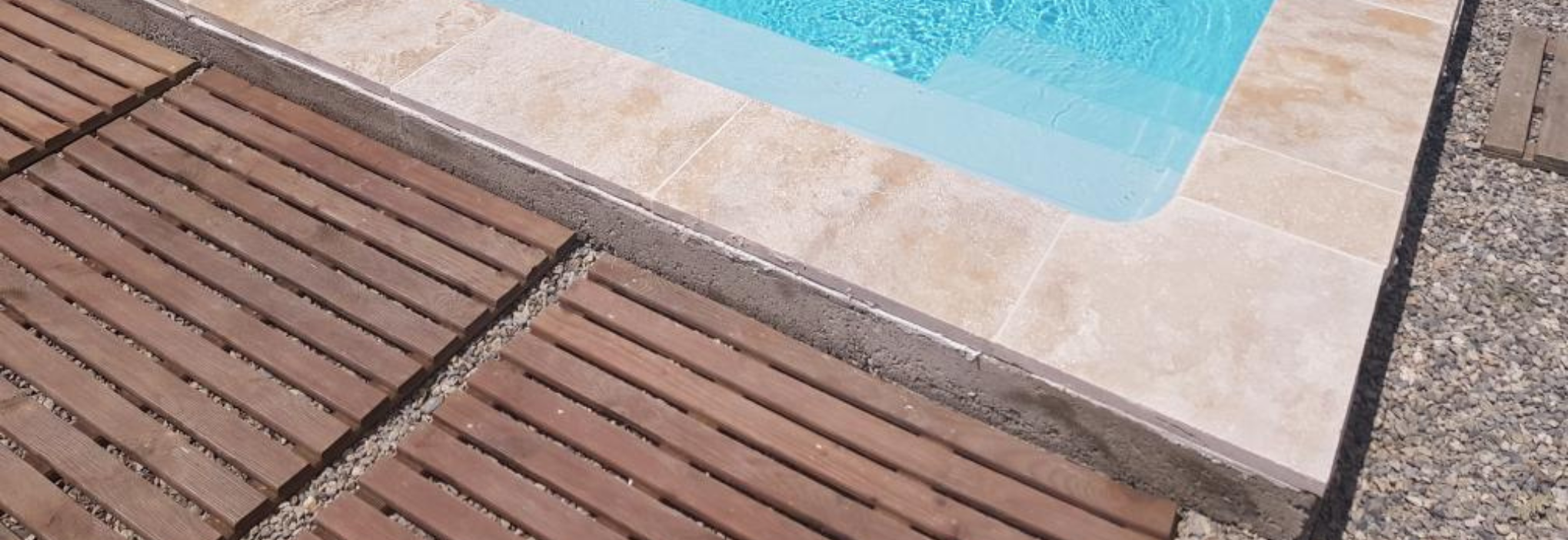 Piscine moderne avec margelles en travertin Light Mix et plage en pierre naturelle.