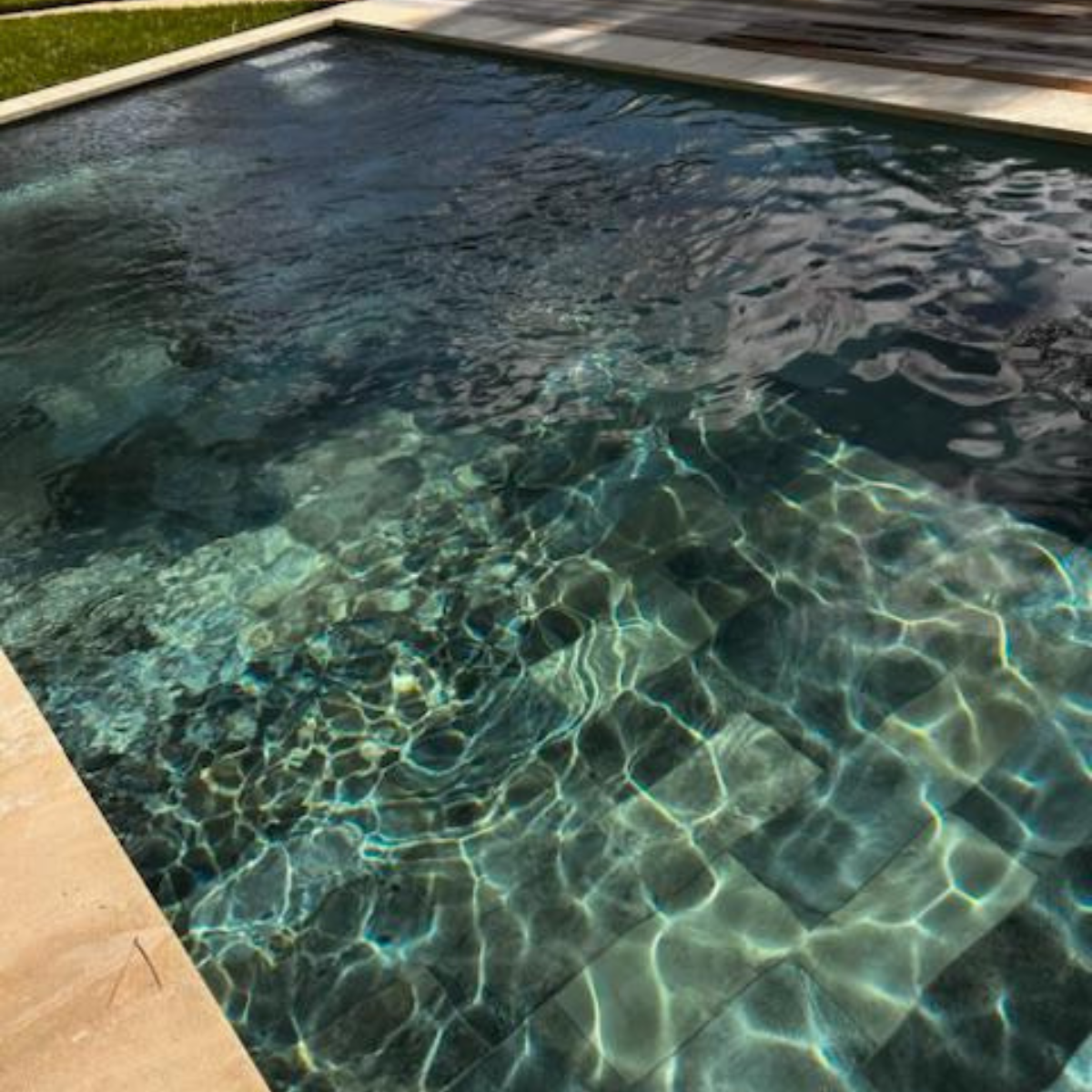 Chaise en fer forgé élégante avec coussin clair, installée sur une terrasse lumineuse avec décor méditerranéen et table de café.