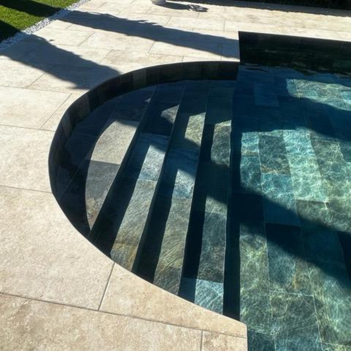 Chaise en fer forgé artisanale avec dossier arrondi et coussin beige, posée sur une terrasse fleurie en extérieur.