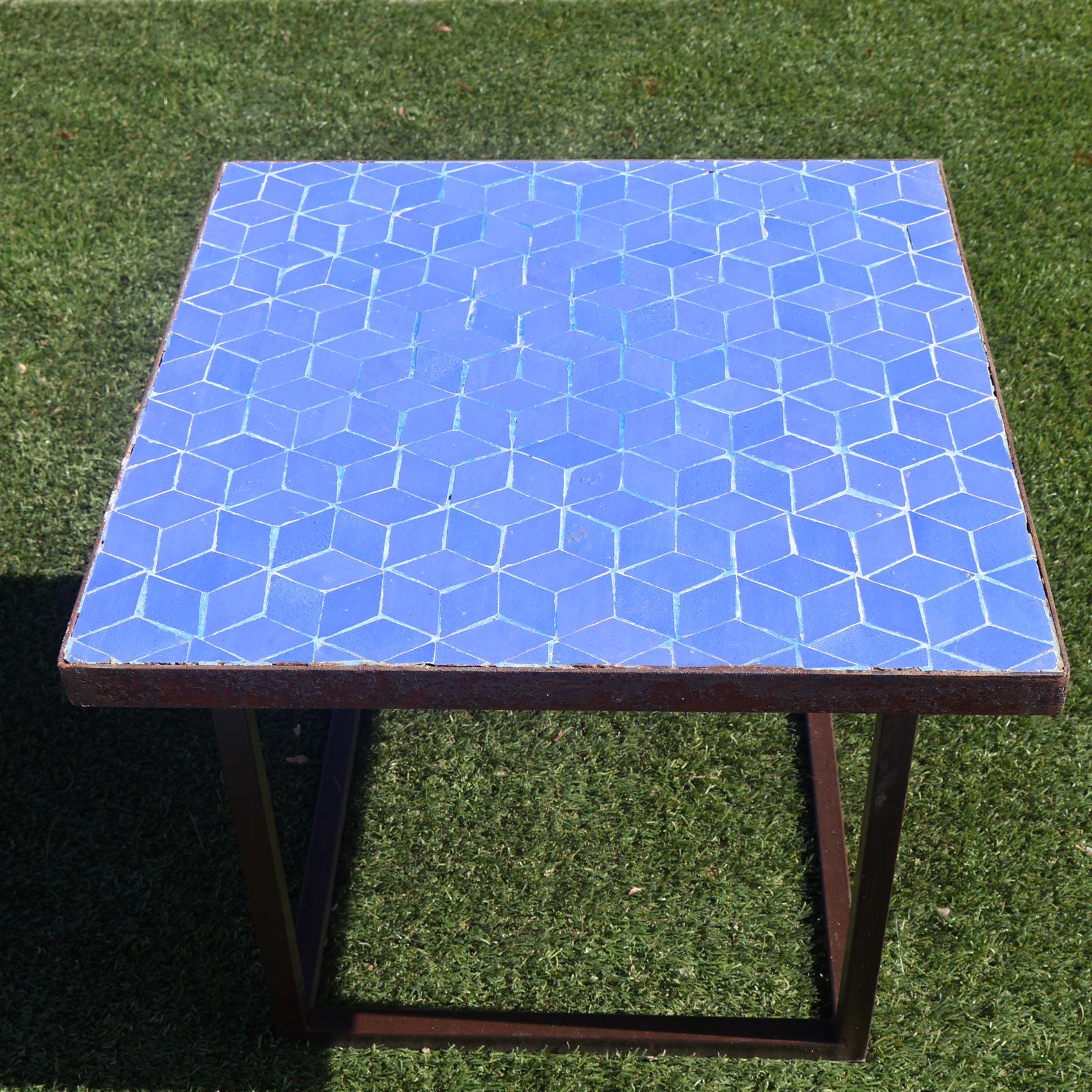 Chaise en fer forgé élégante avec coussin clair, installée sur une terrasse lumineuse avec décor méditerranéen et table de café.