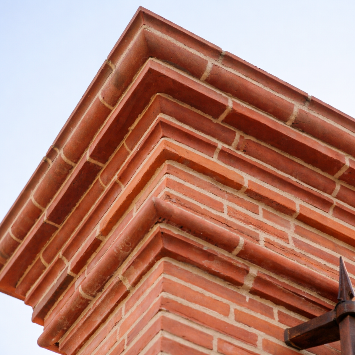 Fauteuil rond en fer forgé avec coussins beige, installé dans un salon chaleureux près d'une cheminée en pierre.
